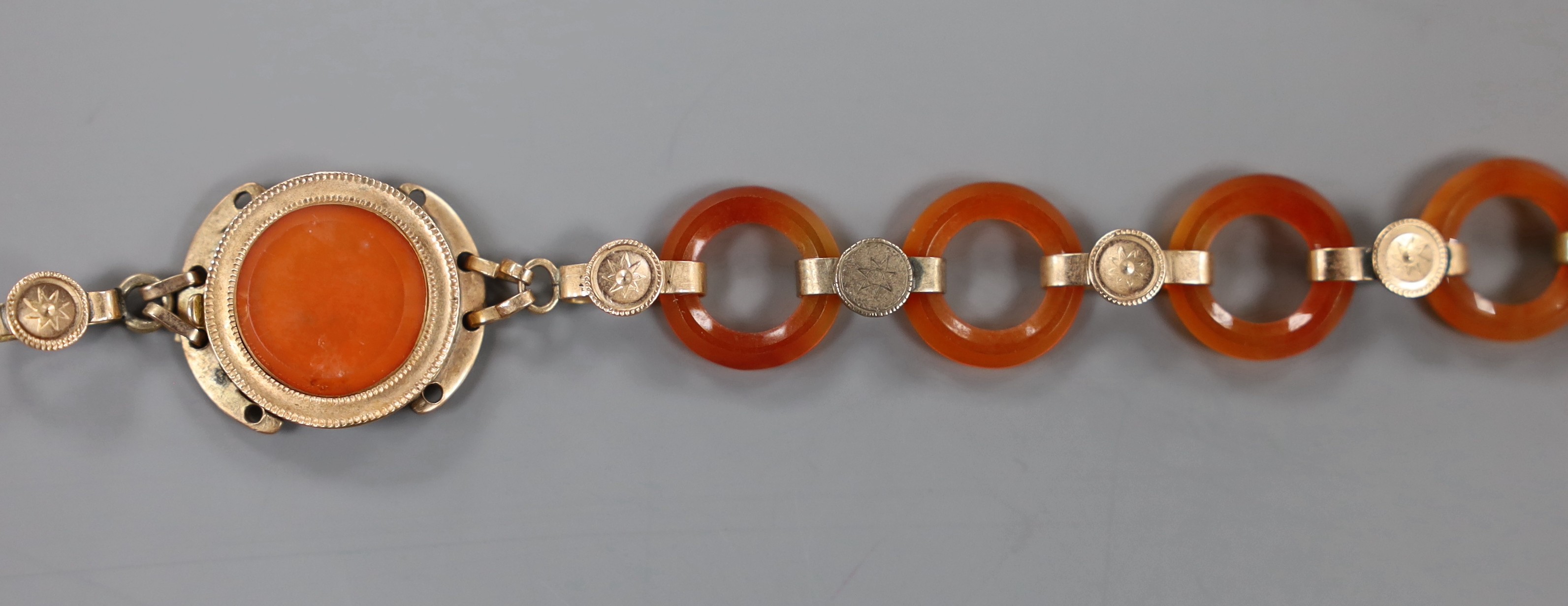 Part of an early 20th century yellow metal and carnelian disc link set bracelet, 14.6cm, gross weight 7.3 grams.